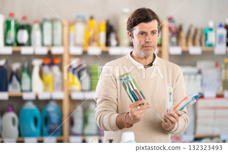 Adult man choosing toothbrush in store Adult man choosing toothbrush in store 132323493