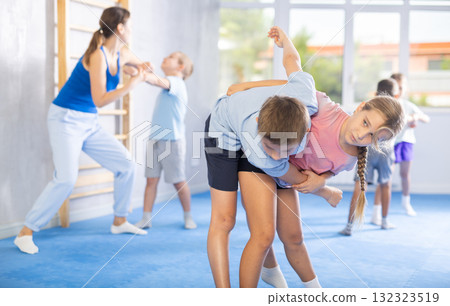 Children, boy and girl, working in pair mastering new self-defense moves at gym Children, boy and girl, working in pair mastering new self-defense moves at gym 132323519