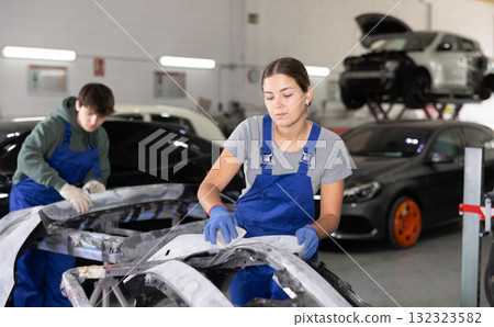 Young female auto mechanic sanding car bumper with sandpaper Young female auto mechanic sanding car bumper with sandpaper 132323582