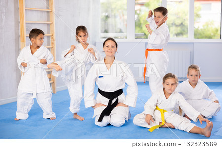 Team of young martial arts athletes is standing in gym with female coach. 132323589