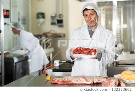 Butcher shop worker holding plastic tray with raw veal fillet 132323602