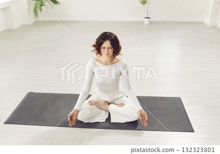 Yogi sporty attractive woman practicing yoga, doing Ardha Padmasana exercise, meditating  132323801