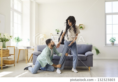 Couple conflict and quarrel at home, man kneeling before woman in living room Couple conflict and quarrel at home, man kneeling before woman in living room 132323803