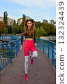 Young Woman Jogging on Bridge in Park with Vibrant Autumn Foliage 132324439