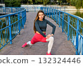 Young Woman Exercising Outdoors on a Bridge in Comfortable Sporty Outfit 132324446