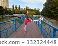 Woman Stretching on Bridge in Park on a Sunny Day in Sportswear 132324448