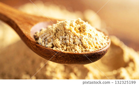 ashwagandha root powder on a wooden spoon, softly lit with warm tones. The natural texture and earthy color convey a sense of organic wellness and adaptogenic nutrition 132325199