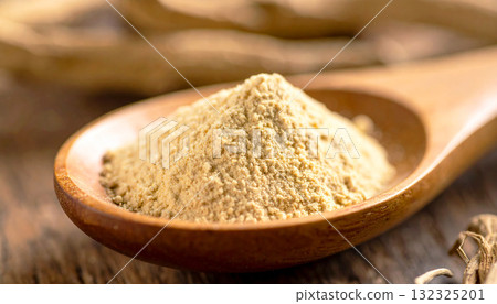 ashwagandha root powder on a wooden spoon, softly lit with warm tones. The natural texture and earthy color convey a sense of organic wellness and adaptogenic nutrition 132325201