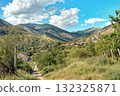 Scenic landscape view of valley with mountains and small village. Green hills and summer sky showing peaceful rural nature environment. 132325871