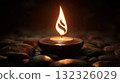 Soft Flame of Candlelight Glowing on Smooth Stones in a Dark Serenity Setting 132326029