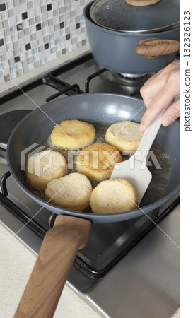 Anonymous person fries potato croquettes in vegetable oil in new, trendy frying pan. Farm produce. Home cooking. Traditional cuisine. Anonymous person fries potato croquettes in vegetable oil in new, trendy frying pan. Farm produce. Home cooking. Traditional cuisine. 132326123