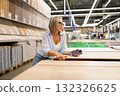 Woman shopping for wood materials in a home improvement store during daytime 132326625