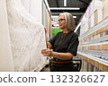 Woman selecting fabric in a modern home decor store during daylight with shelves of supplies in the 132326627