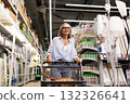 Woman shopping in a well-stocked retail store with a shopping cart during daytime 132326641