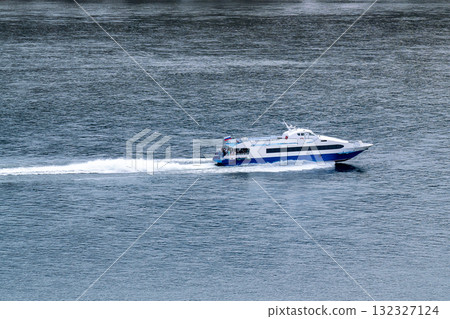 A pleasure boat with passengers sails along the river bank. 132327124