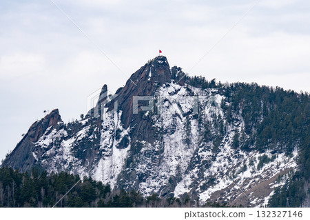 A majestic rock with a red flag on the mountaintop. A majestic rock with a red flag on the mountaintop. 132327146