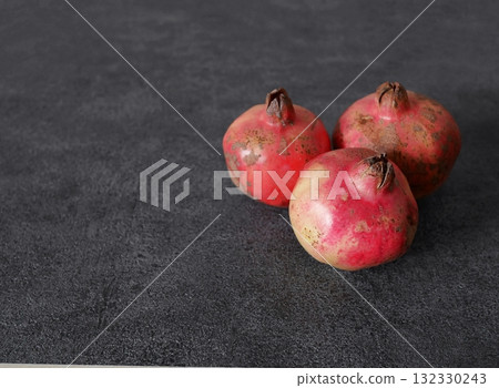 Three Japanese pomegranates, right-justified, with white space on the left, on a gray background 132330243