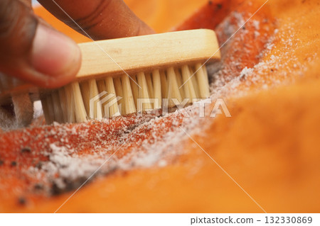 Cleaning a vibrant orange fabric with a brush 132330869
