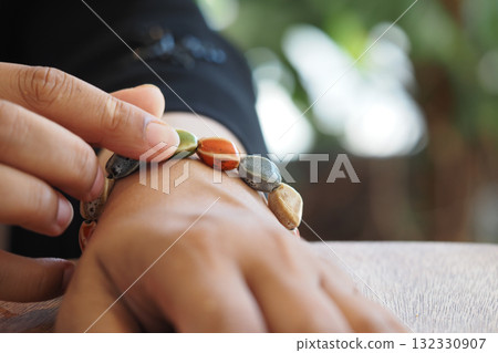 Hand adjusting colorful stone bracelet in a sunny setting 132330907