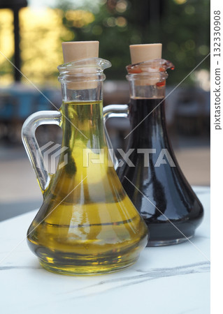 Oil and vinegar in glass bottles on a table outdoors Oil and vinegar in glass bottles on a table outdoors 132330908