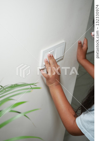 A child is switching off the lights in a warm, inviting room A child is switching off the lights in a warm, inviting room 132330974