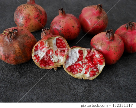 Several Japanese pomegranates, one split in half, grey background, white space below Several Japanese pomegranates, one split in half, grey background, white space below 132331117