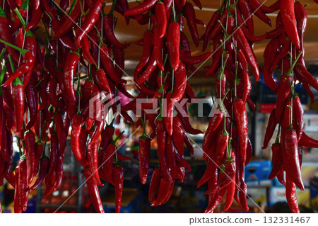 Organic red hot chili peppers hanging outdoors on market, closeup Organic red hot chili peppers hanging outdoors on market, closeup 132331467