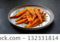 Honey-glazed roasted carrots sprinkled with fresh herbs on a serving plate 132331814