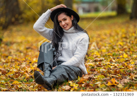 Young beautiful brunette woman in a white sweater and black hat in an autumn park Young beautiful brunette woman in a white sweater and black hat in an autumn park 132331969