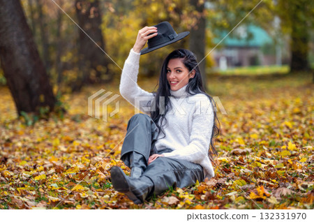 Young beautiful brunette woman in a white sweater and black hat in an autumn park Young beautiful brunette woman in a white sweater and black hat in an autumn park 132331970
