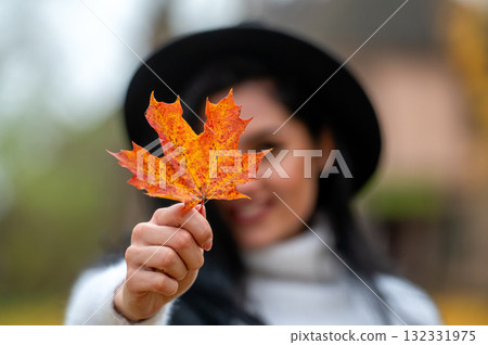 Portrait of a beautiful young woman in the autumn park with maple leaf 132331975