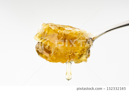 Honey dripping from a honeycomb scooped up with a spoon Honey dripping from a honeycomb scooped up with a spoon 132332165