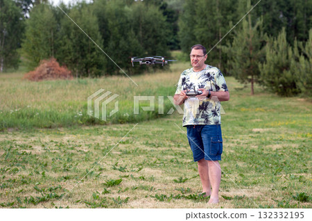 A man operating the drone by remote control on the meadow. A man operating the drone by remote control on the meadow. 132332195