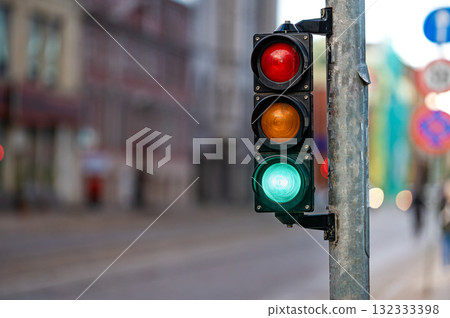 view of city traffic with traffic lights, in the foreground a semaphore with a green light, closeup 132333398