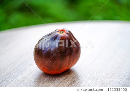 fresh picked multicolored striped and streaky black, purple, and red tomatoes on a wooden table 132333400