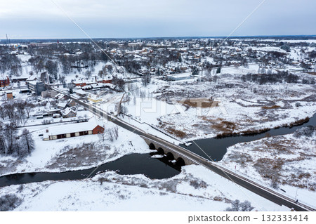 An old stone bridge with arches over the Abava river on a snowy winter day, Kandava, Latvia 132333414