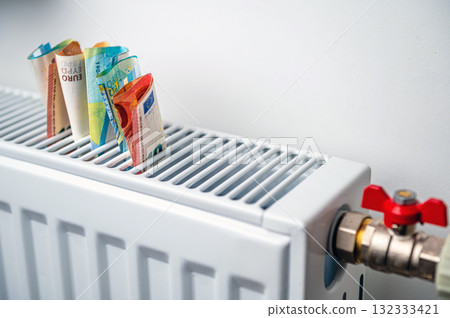 euro banknotes in a central heating radiator, the concept of expensive heating costs, closeup euro banknotes in a central heating radiator, the concept of expensive heating costs, closeup 132333421