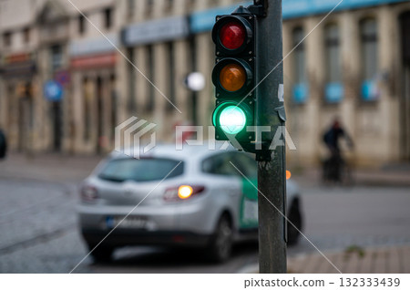 view of city traffic with traffic lights, in the foreground a semaphore with a green light, closeup 132333439