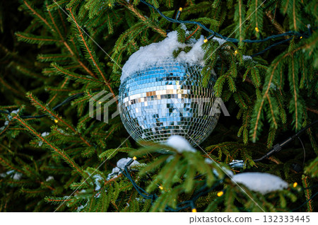 Christmas disco ball decoration on a snowy Christmas tree branch. Selective focus 132333445