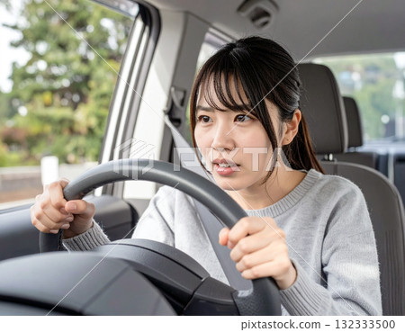 一名年輕女子是一名紙本司機,她膽怯地開車 一名年輕女子是一名紙本司機,她膽怯地開車 132333500
