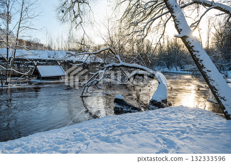 river with leaning snow-covered tree in winter at sunrise river with leaning snow-covered tree in winter at sunrise 132333596