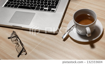 Desk with laptop, eyeglasses and a cup of tea on a wooden table - image Desk with laptop, eyeglasses and a cup of tea on a wooden table - image 132333604