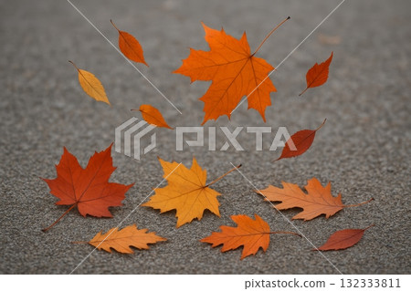 Falling autumn leaves in shades of orange and red, creating a beautiful seasonal scene on textured ground. 132333811