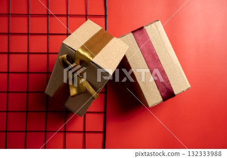 Top view of a brown gift box tied with a golden and red ribbon on a colored background. Mockup or copy space. Concept of decoration for holidays, anniversaries, celebrations, presents, or surprises Top view of a brown gift box tied with a golden and red ribbon on a colored background. Mockup or copy space. Concept of decoration for holidays, anniversaries, celebrations, presents, or surprises 132333988
