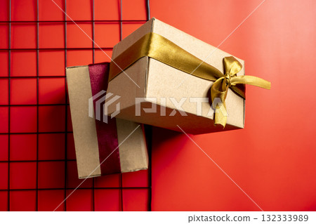 Top view of a brown gift box tied with a golden and red ribbon on a colored background. Mockup or copy space. Concept of decoration for holidays, anniversaries, celebrations, presents, or surprises Top view of a brown gift box tied with a golden and red ribbon on a colored background. Mockup or copy space. Concept of decoration for holidays, anniversaries, celebrations, presents, or surprises 132333989