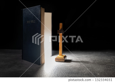 Blue book of the Holy bible and Christian cross. Standing on the table with a dark background. Symbol of faith in God. Concept of Spirituality, Christianity, religion, faith, Jesus, or belief 132334031