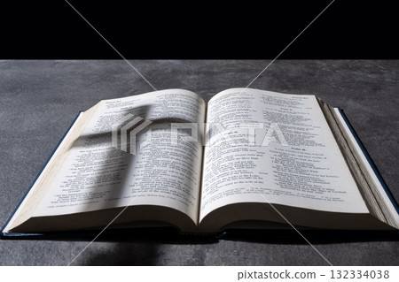 Blue book of Holy bible and silhouette of a Christian cross. Standing on table with a dark background. Symbol of faith in God. Concept of Spirituality, Christianity, religion, faith, Jesus, or belief Blue book of Holy bible and silhouette of a Christian cross. Standing on table with a dark background. Symbol of faith in God. Concept of Spirituality, Christianity, religion, faith, Jesus, or belief 132334038
