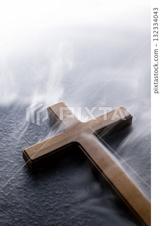 Christian cross on the table with a smoke background. Concept of Christianity, religious, faith, Jesus, or belief 132334043
