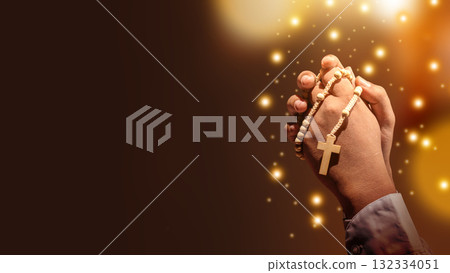 Prayer holding rosary beads with a Christian cross with glitter lights and blurred bokeh lights background. Concept of Christianity, religious, faith, Jesus, or belief 132334051