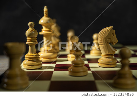 Closeup view of a white chess pawn standing against the opposing pieces on the chessboard. Concept of strategy Closeup view of a white chess pawn standing against the opposing pieces on the chessboard. Concept of strategy 132334056